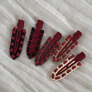 Five vintage red leather wrapped alloy duckbill hair clips on beige fabric