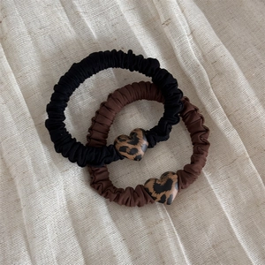 Dettaglio dei ciondoli a cuore leopardato su elastici per capelli neri e marroni