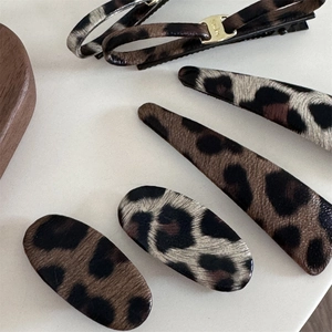 Detail showing five assorted leopard print hair clips with elegant leather texture