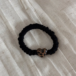 Dettaglio dell'elastico nero con un pendente a cuore lucido con motivo leopardato