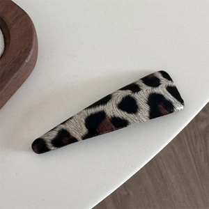 Close-up of leopard print triangular hair clip showing retro velvet texture and pattern
