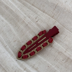 Close-up of vintage burgundy red leather wrapped alloy hairpin with woven texture