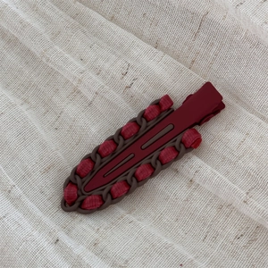 Detail view of red leather wrapped hair clip with chain border on linen texture