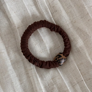 Dettaglio dell'elastico per capelli marrone con fibbia geometrica a macchie di leopardo