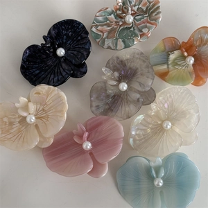 Close-up of acetic acid orchid flower hair clips with pearl center in multiple colors
