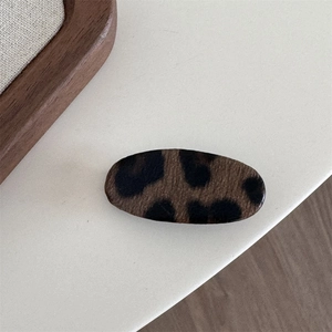 Close-up of an oval leopard print hair clip with matte texture and vintage aesthetic