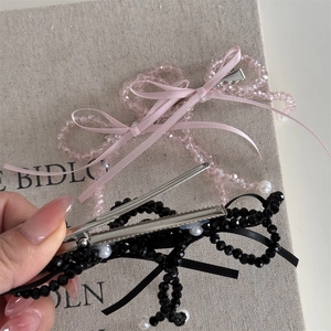 Detailed view of beaded bow hair clips with silk ribbons in pink and black colors