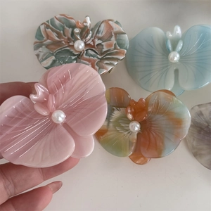 Detailed close-up of a 3D orchid acetate hair clip with a faux pearl center decoration