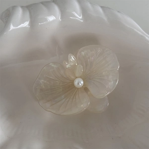 Detail of orchid hair clip with creamy iridescent acetate petals and a center pearl