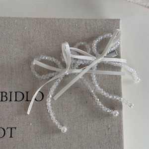 Detail of beaded bow hair clip with crystal beads and elegant white ribbon texture