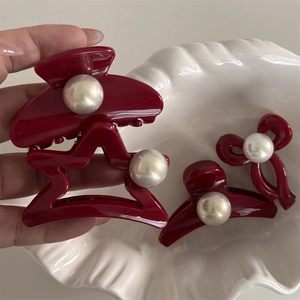 Elegant wine red hair claw set with white pearls in star and bow shapes on ceramic dish