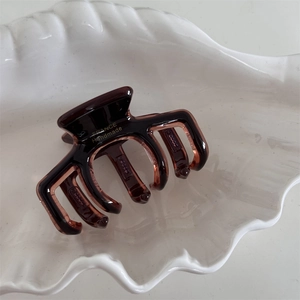 Close-up of translucent amber acetate hair claw with gold France Handmade lettering