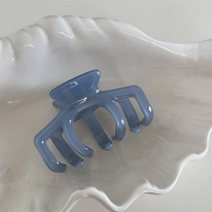 Detail of grey-blue acetate shark hair claw clip with Handmade text in a shell tray