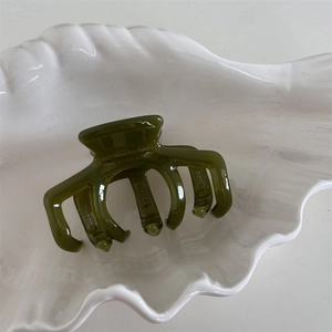 Detailed macro view of olive green acetate hair claw with France Handmade gold engraving