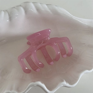 Detailed close-up of pink acetate hair claw with France Handmade text on white shell tray