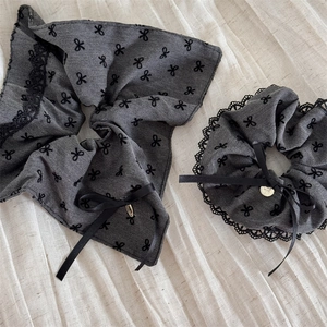 Detailed macro view of grey lace hair scrunchie with black bow pattern and silk ribbon