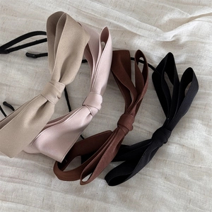 Dettaglio di cerchietti in tessuto a più strati con fiocchi in beige, rosa, marrone e nero