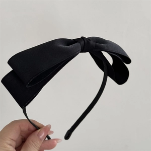 Primo piano di un elegante cerchietto con doppio fiocco in tessuto nero e base in metallo