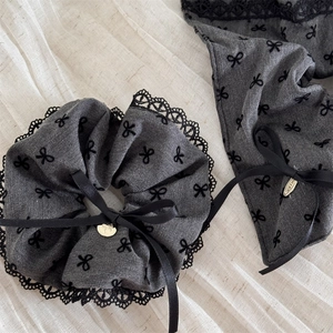 Elegant grey lace scrunchie with black bow pattern and a small gold charm pendant