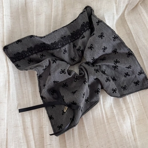 Close-up of grey lace scrunchie with black bow pattern and elegant ribbon detail
