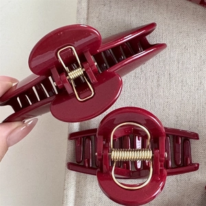 Close-up of wine red glitter resin hair claw clips with gold metal spring mechanism