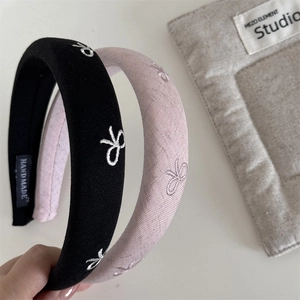 Detail of handmade wide headbands with bow embroidery in black and light pink colors