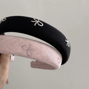 Close-up of padded headband featuring delicate butterfly embroidery in black and pink fabric