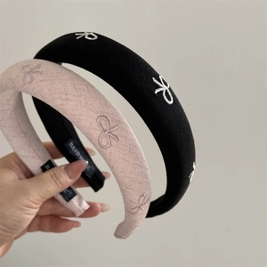 Detail showing embroidered bow on thick sponge headband with handmade inner tag