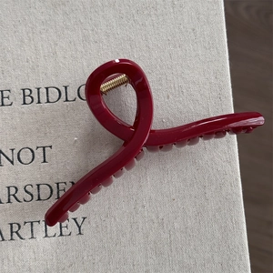 Detail view of a large wine red hair claw clip with a glossy finish and gold spring