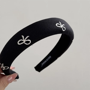 Detailed macro view of black sponge headband showing embroidery and Hand Made label