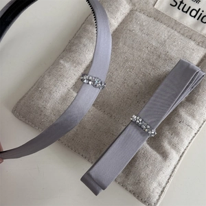 Detail von grauem Satin-Haarband-Set mit funkelndem Kristallbesatz und feiner Textur