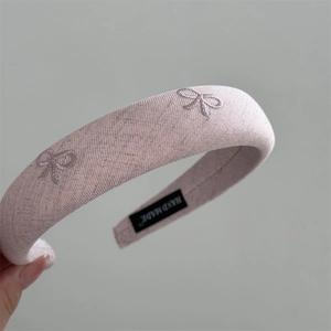 Detailed close-up of pink embroidered bow headband featuring a handmade inner label tag