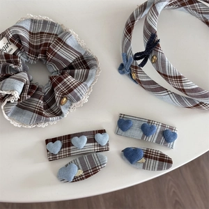 Detailed view of blue plaid hair accessories with lace trim and heart shaped fabric patches