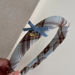 Close-up of blue British plaid headband fabric and golden love metal plate detail