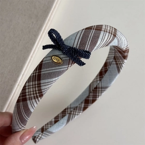 Detail of blue plaid fabric headband with a denim bow and a golden 'love' metal plate