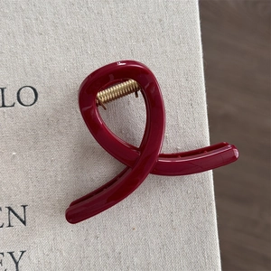 Close-up of elegant deep red hair claw clip with golden glitter and sleek ribbon design