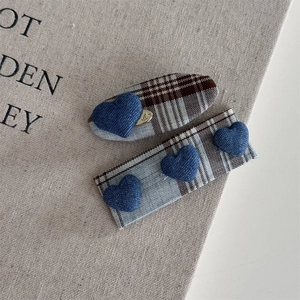 Detailed view of British plaid hair clips featuring blue denim heart motifs and gold accents
