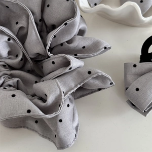 Détail macro du chouchou en tissu gris à pois avec des plis à texture sergée premium