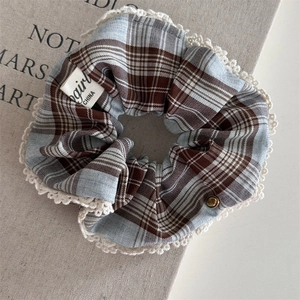 Detail view of British blue plaid hair clip with white lace trim and gold metal button