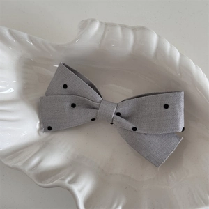 Détail d'un nœud papillon en tissu gris à pois avec bords bruts sur plateau blanc