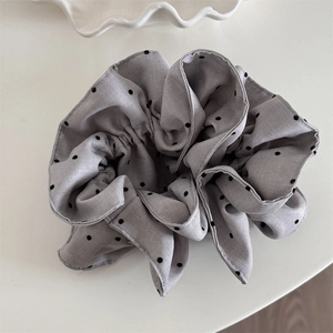 Détail du chouchou en tissu gris à pois noirs montrant la texture du coton tissé