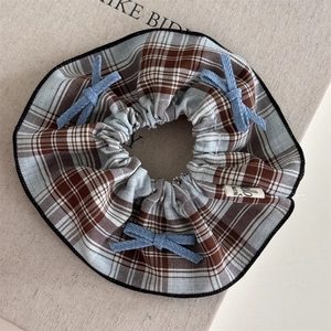 Detail of blue plaid hair scrunchie with light blue bows and vintage Hello woven label