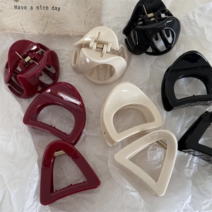 Triangle hair claws in red, cream, and black colors with glossy finish and metal springs