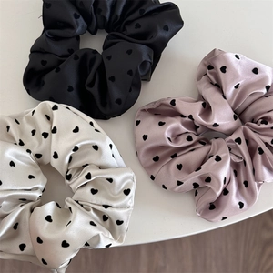Three-piece satin scrunchie set with heart patterns in black, light pink, and beige colors