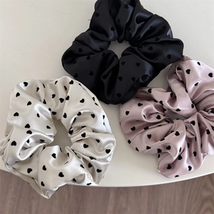 Elegant satin scrunchies with heart patterns in black, off-white, and dusty pink