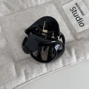 Close-up of a glossy black triangular hair claw clip with a durable silver metal spring
