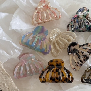 Collection of acetate ocean shell hair claws with marble and floral patterns on white paper