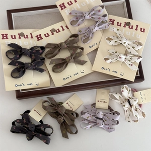 Set de pinzas y coleteros de tela con estampado floral en varios colores en bandeja de madera