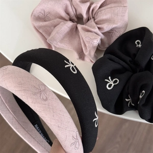 Détail montrant la texture du tissu et la broderie de nœud sur les bandeaux de cheveux