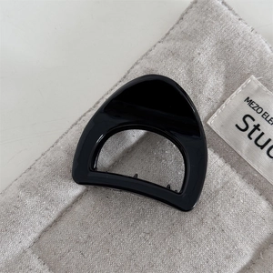 Detail view of small triangle hair claw clip in glossy black finish on canvas background